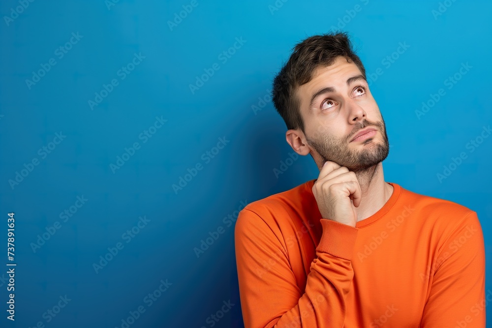 A man wearing an orange shirt looks up towards the sky. A man wearing an orange shirt looks up towards the sky.