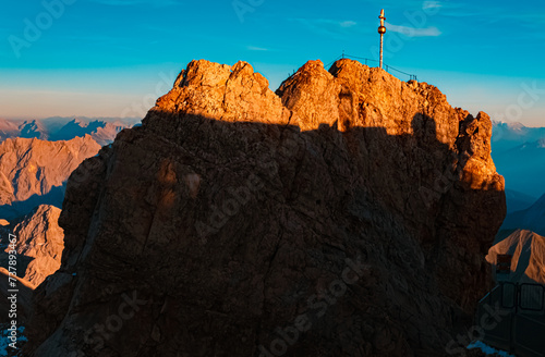 Alpine sunset or sundowner with a golden summit cross at Mount Zugspitze, Top of Germany, Garmisch-Partenkirchen, Bavaria, Germany
