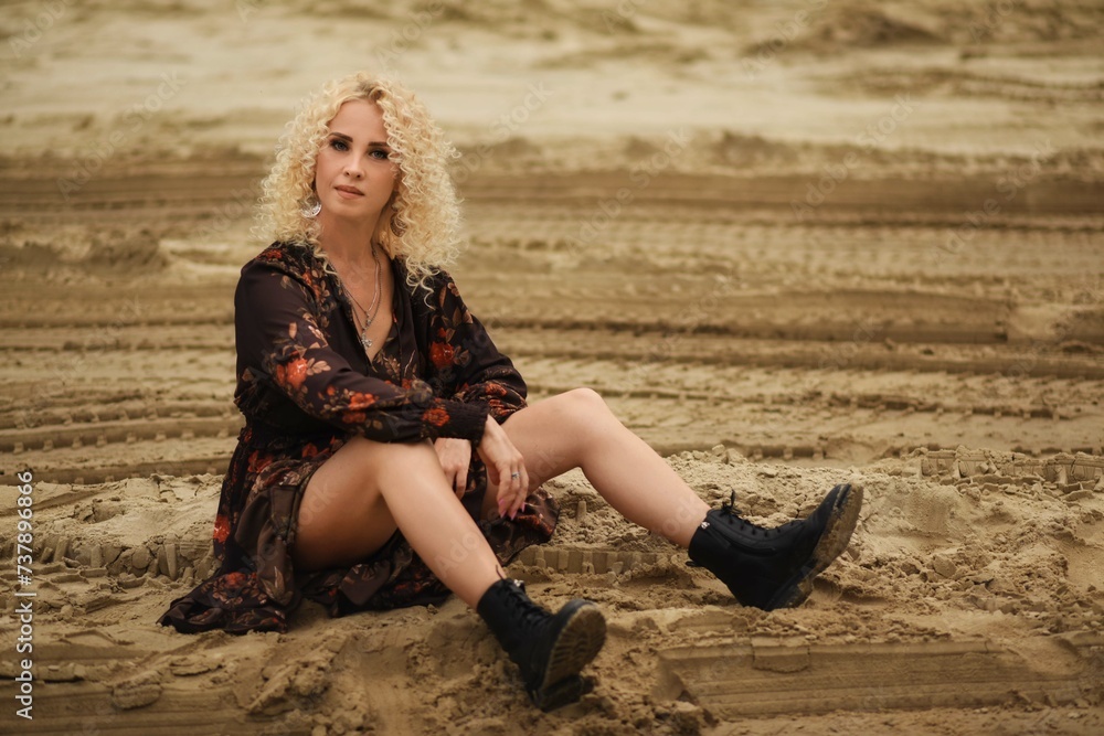Portrait of a beautiful young woman. Blonde with curly hair. Woman on the beach in a dress