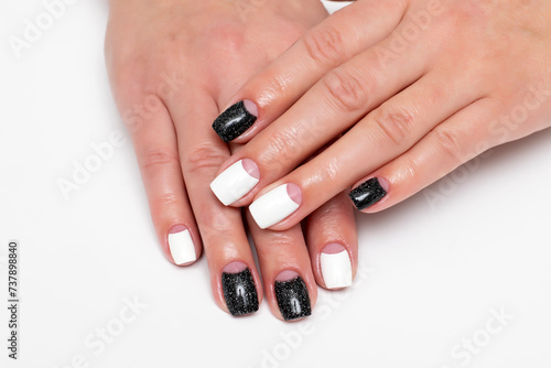 Black and white lunar manicure with shimmer on short square nails close-up on a white background. Reflective black color.