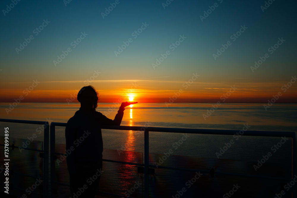 Girl silhouette with sun on the palm in magical sunset over the Gulf of Finland, Baltic sea.