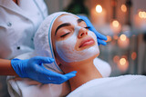 Beautician doing facial skin care for Hispanic girl in beauty salon