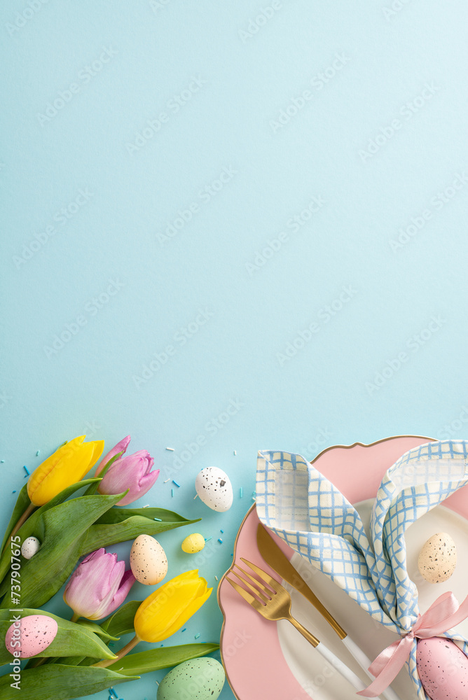 Whimsical Easter table: vertical top view of funny ears napkin, plate, cutlery, tulips, sprinkles, and eggs on a pastel blue surface. Create a charming atmosphere for your Easter feast