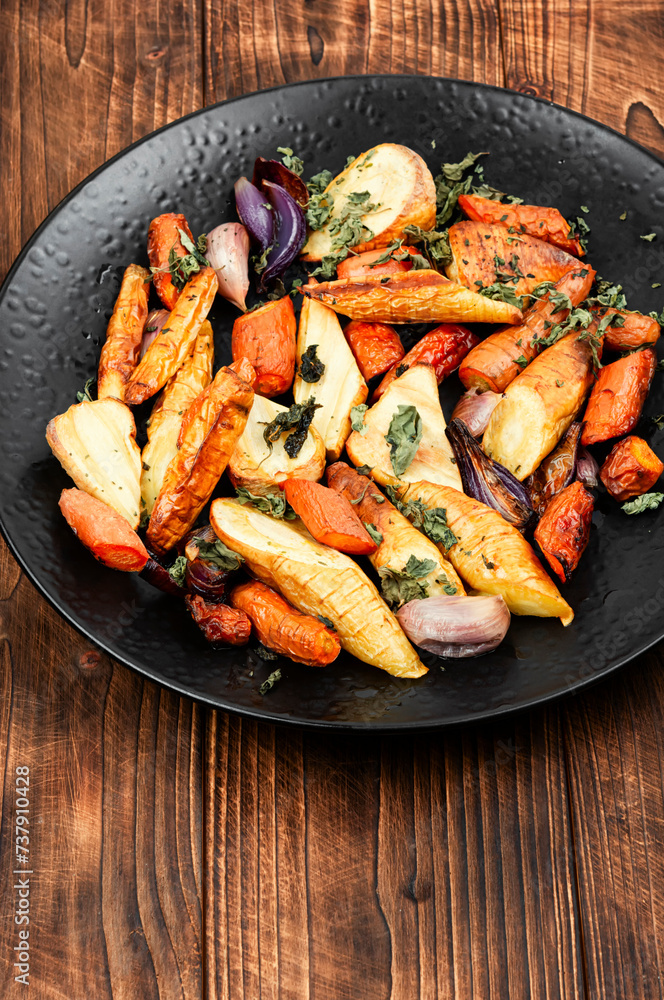 Baked parsnip root and carrots on a wooden table. Baked parsnip root and carrots on a wooden table.