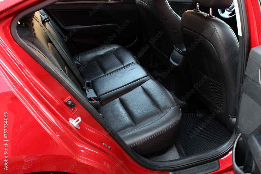 Back passenger seats in modern luxury car. Black leather rear seats. Three in the row. Frontal view, perforated black leather with stitching. Heated and ventilated seats. 