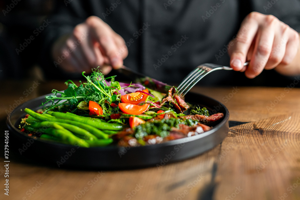 Hands of a man with a fork and knife eat Salad Hands of a man with a fork and knife eat Salad