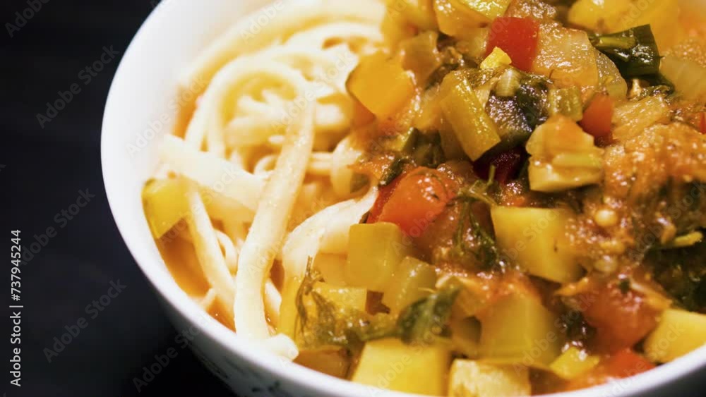 Stewed vegetables with meat and noodles in a bowl. Lagman. Black background. Stewed vegetables with meat and noodles in a bowl. Lagman. Black background.