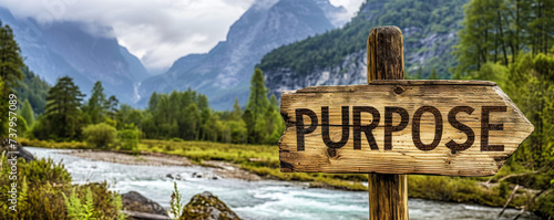 Rustic wooden signpost with the word PURPOSE pointing forward against a backdrop of majestic mountains and river, symbolizing direction, goal setting, and life's journey photo