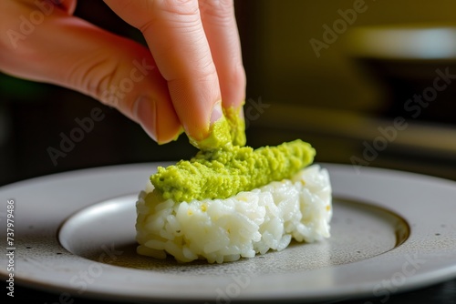 hand dapping wasabi onto nigiri rice base photo