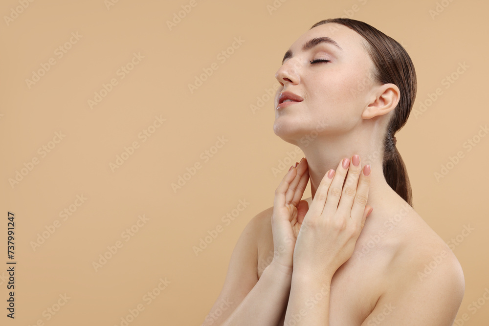 Fototapeta premium Beautiful woman touching her neck on beige background. Space for text
