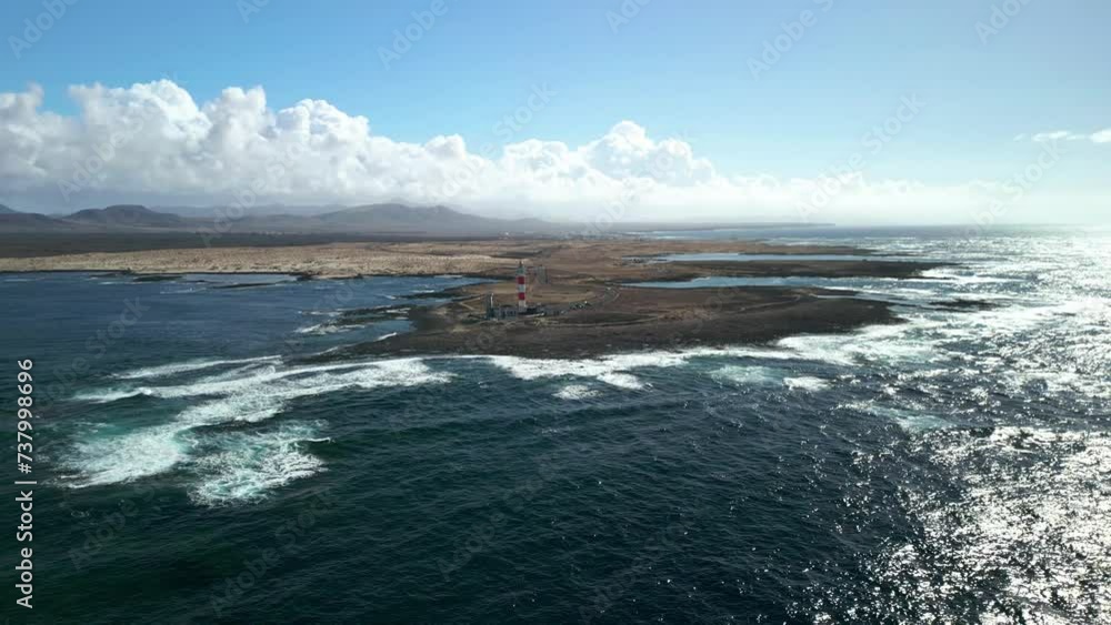 The 19th century red and white bands Faro del Tostón lighthouse located on the northwest coast of Fuerteventura in the Canary Islands. A lighthouse against the background of the blue sky and the ocean The 19th century red and white bands Faro del Tostón lighthouse located on the northwest coast of Fuerteventura in the Canary Islands. A lighthouse against the background of the blue sky and the ocean