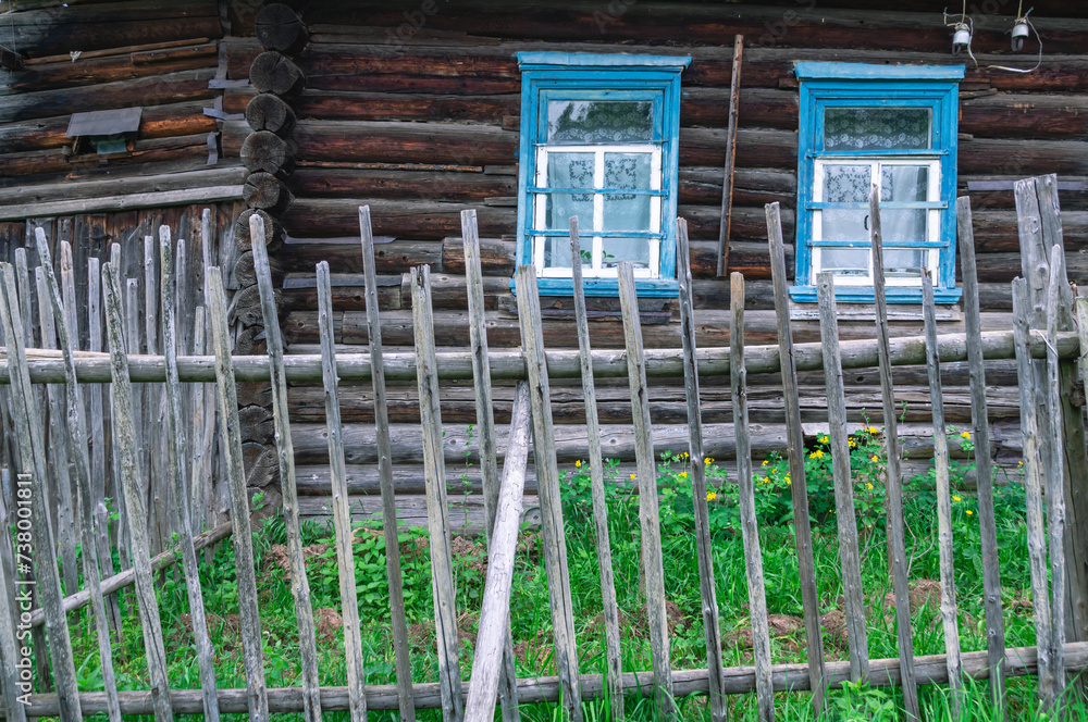 A stockade in the village. A fence in the village. A wooden village house is visible behind the fence. An old wooden house in the village. A stockade in the village. A fence in the village. A wooden village house is visible behind the fence. An old wooden house in the village.