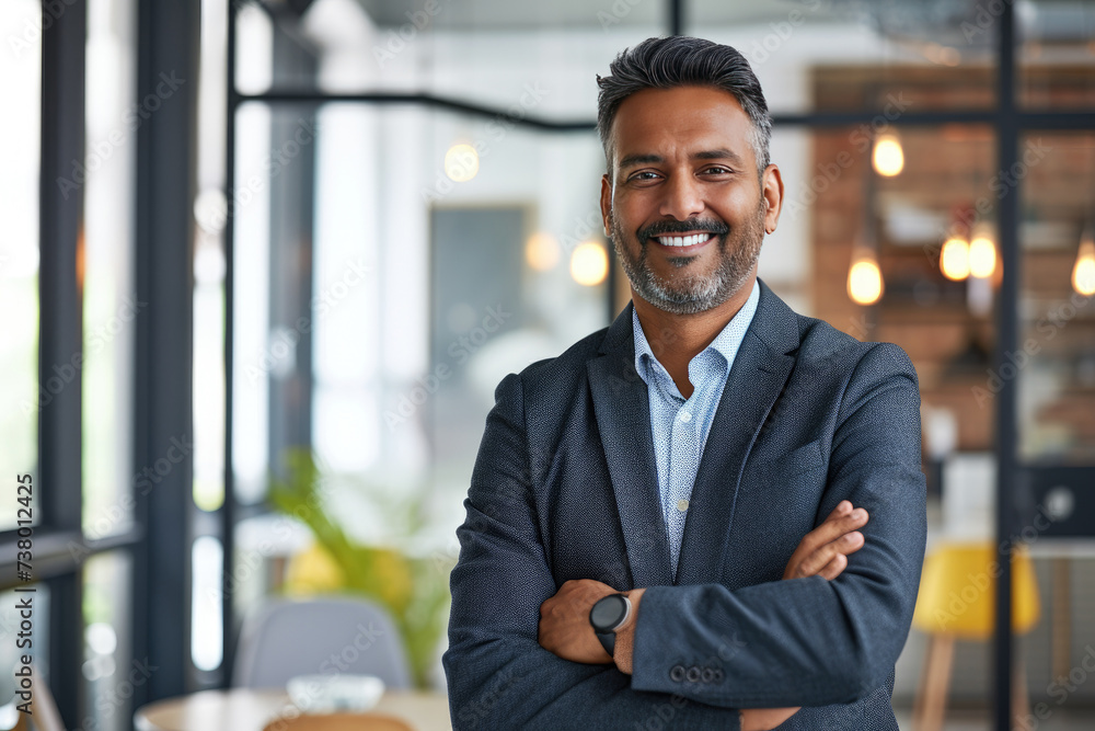 Cheerful Indian businessman with a bright smile in a modern workplace Cheerful Indian businessman with a bright smile in a modern workplace