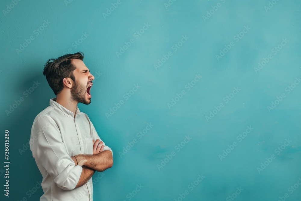 A man with his arms crossed on his chest shouts on turquoise background - obrazy, fototapety, plakaty 