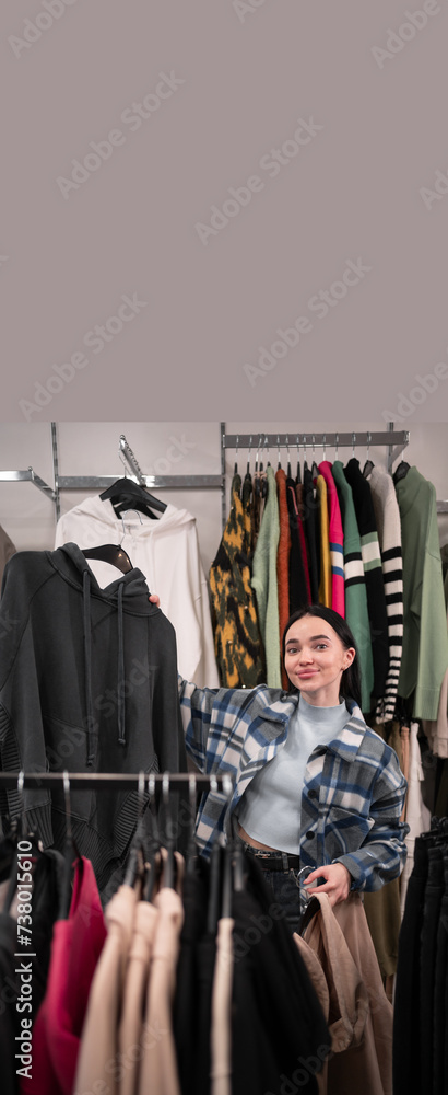 Young customer woman holding sweaters at clothing store worry for choice with sad expression. Copy space