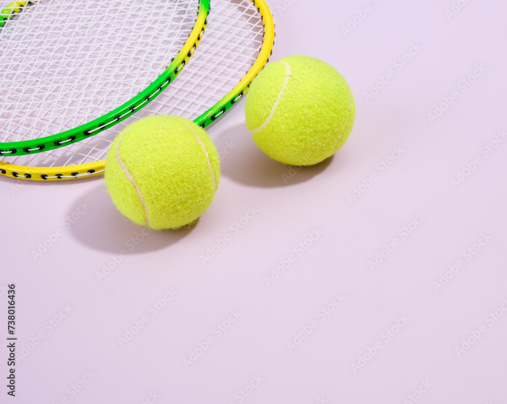 Sports composition with yellow bright tennis balls and rackets on a purple background. Copy space for text. Health and sports.