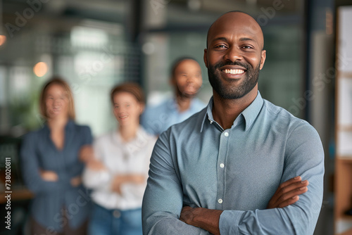 Handsome and confident African American businessman consultant smiling with diversity team in modern office background © boxstock production