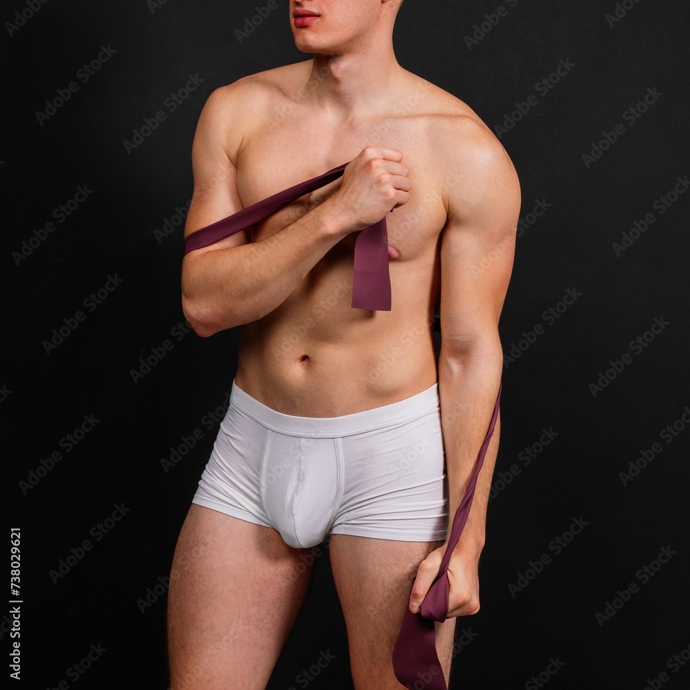 Young bodybuilder working out with rubber band over white and dark background Young bodybuilder working out with rubber band over white and dark background