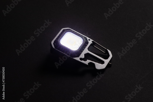LED Flashlight Keychain and a beam of light in darkness. A modern led lamp with bright projection on dark table.