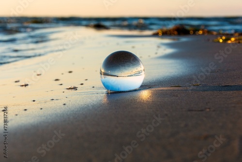 Beach and sea reflected in a sphere lying in the sand in the waves