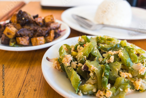 Ginisang ampalaya with egg, known as Sauteed Bitter Melon, served with tokwa baboy and rice at a Filipino restaurant. photo