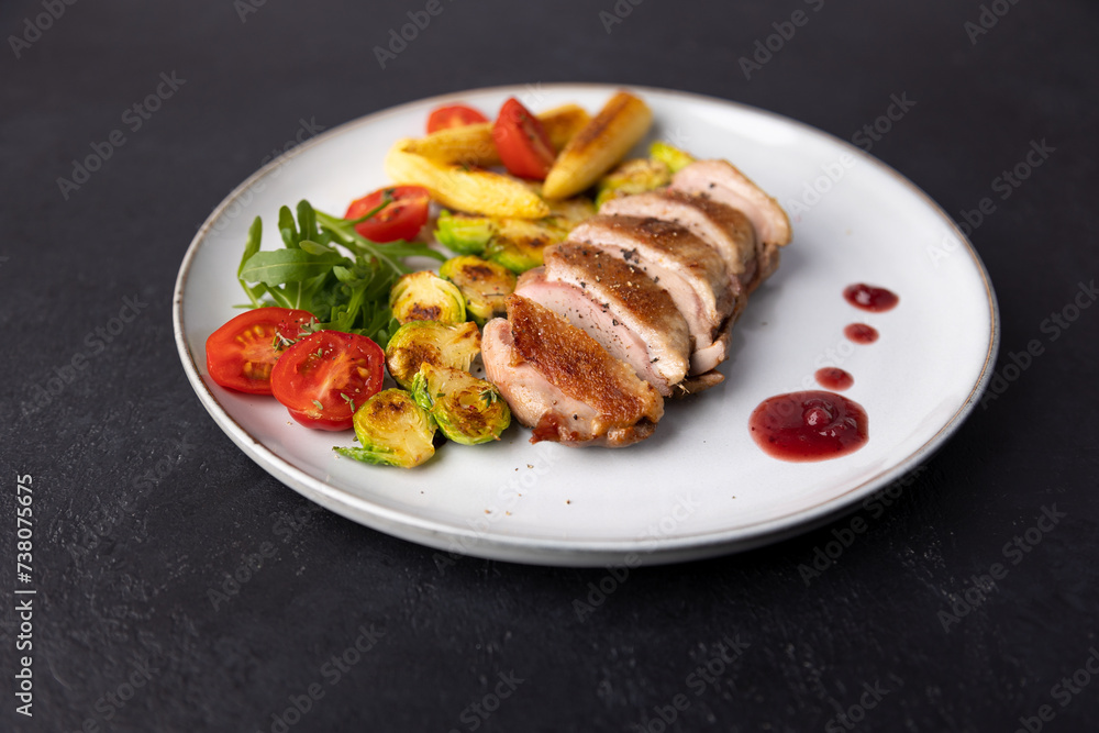 Grilled duck breast fillet with Brussels sprouts, mini corn, cherry tomatoes, arugula and lingonberry sauce. Traditional Mediterranean cuisine. Selective focus, close-up. Grilled duck breast fillet with Brussels sprouts, mini corn, cherry tomatoes, arugula and lingonberry sauce. Traditional Mediterranean cuisine. Selective focus, close-up.