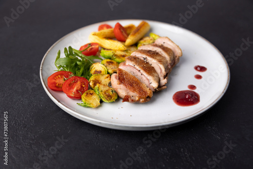 Grilled duck breast fillet with Brussels sprouts, mini corn, cherry tomatoes, arugula and lingonberry sauce. Traditional Mediterranean cuisine. Selective focus, close-up.