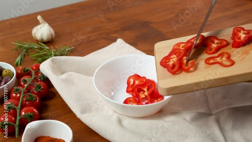 Putting the red pepper in the bowl on artizan wooden table photo