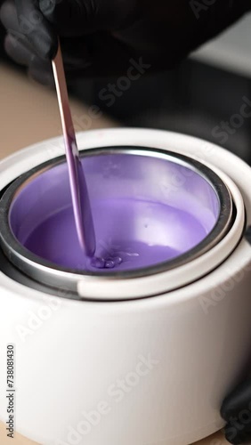 Master mixes the heating wax with a wooden spatula before the depilation procedure. Depilation with wax