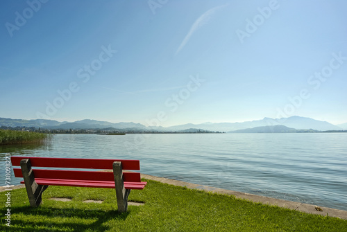 Zwei rote Sitzbänke am Zürichsee mit Sicht auf die Alpen