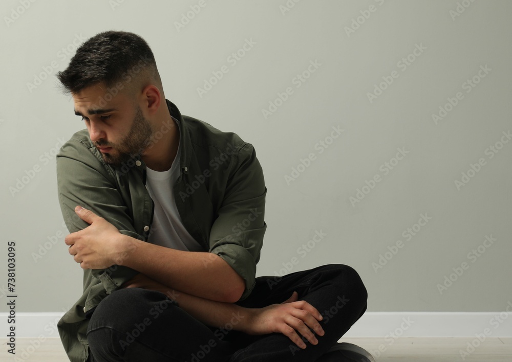 Sad man sitting near light grey wall. Space for text Sad man sitting near light grey wall. Space for text