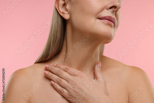 Mature woman with healthy skin on pink background, closeup