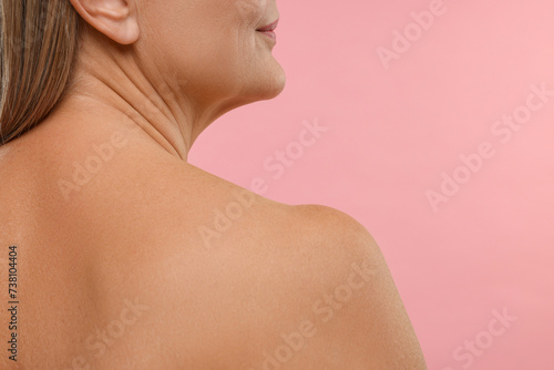 Mature woman with healthy skin on pink background, closeup. Space for text