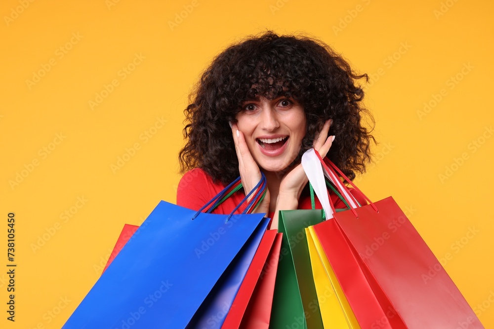 Happy young woman with shopping bags on yellow background Happy young woman with shopping bags on yellow background