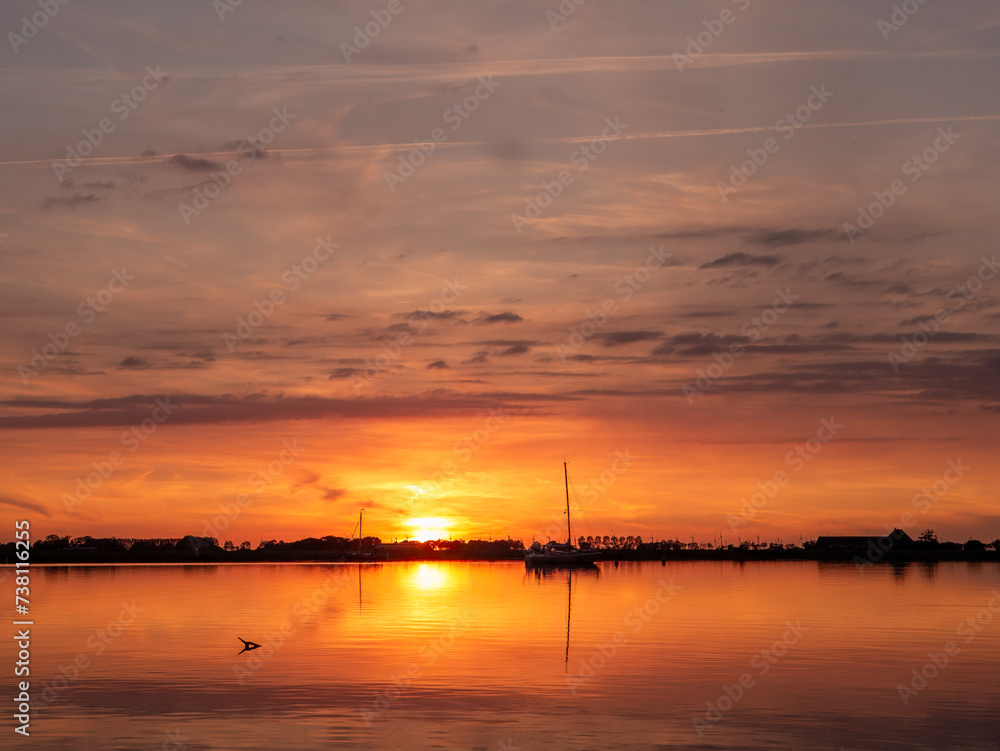 Anchored sailboats at sunset on Lake De Morra, Friesland, Netherlands Anchored sailboats at sunset on Lake De Morra, Friesland, Netherlands