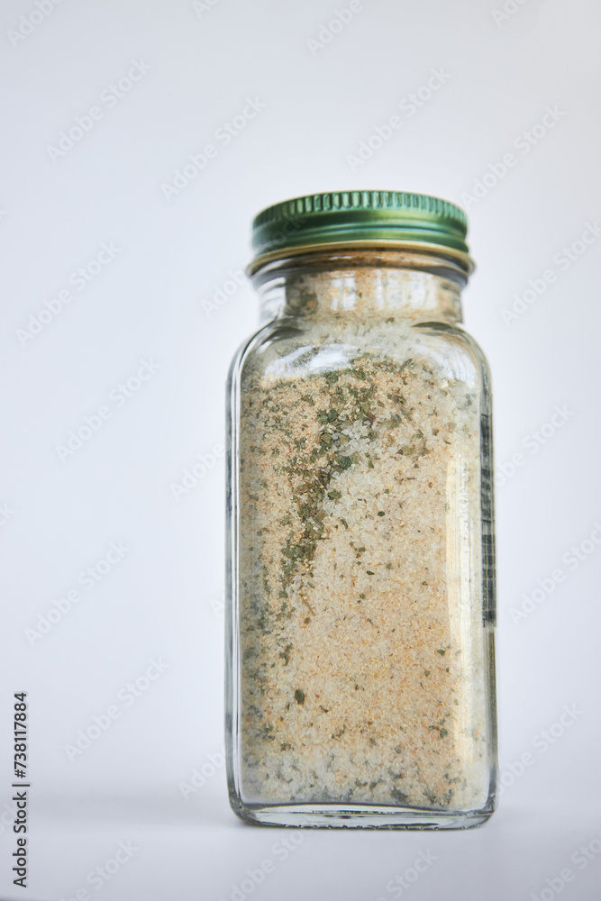 Glass jar with loose dried mixture close-up. Using reusable, recyclable Eco-friendly packaging in everyday life. Organic Seasoning Blend mix. Gray background. Glass jar with loose dried mixture close-up. Using reusable, recyclable Eco-friendly packaging in everyday life. Organic Seasoning Blend mix. Gray background.