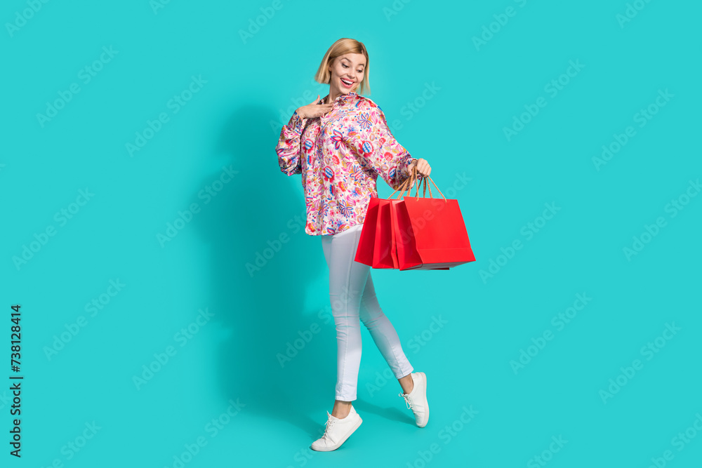 Full size photo of attractive young woman hold shopping bags excited dressed stylish pink clothes isolated on aquamarine color background Full size photo of attractive young woman hold shopping bags excited dressed stylish pink clothes isolated on aquamarine color background