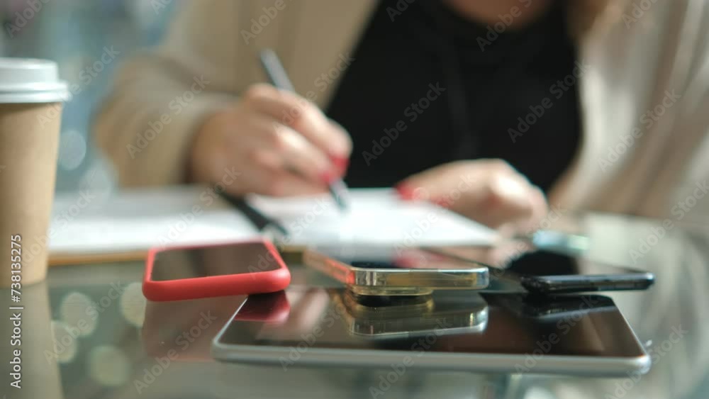 Close-up young lady freelance focus mobile phone chat with colleagues work finance writing on notebook in living room at home. Girl student learn online at house, Work from home concept. Close-up young lady freelance focus mobile phone chat with colleagues work finance writing on notebook in living room at home. Girl student learn online at house, Work from home concept.