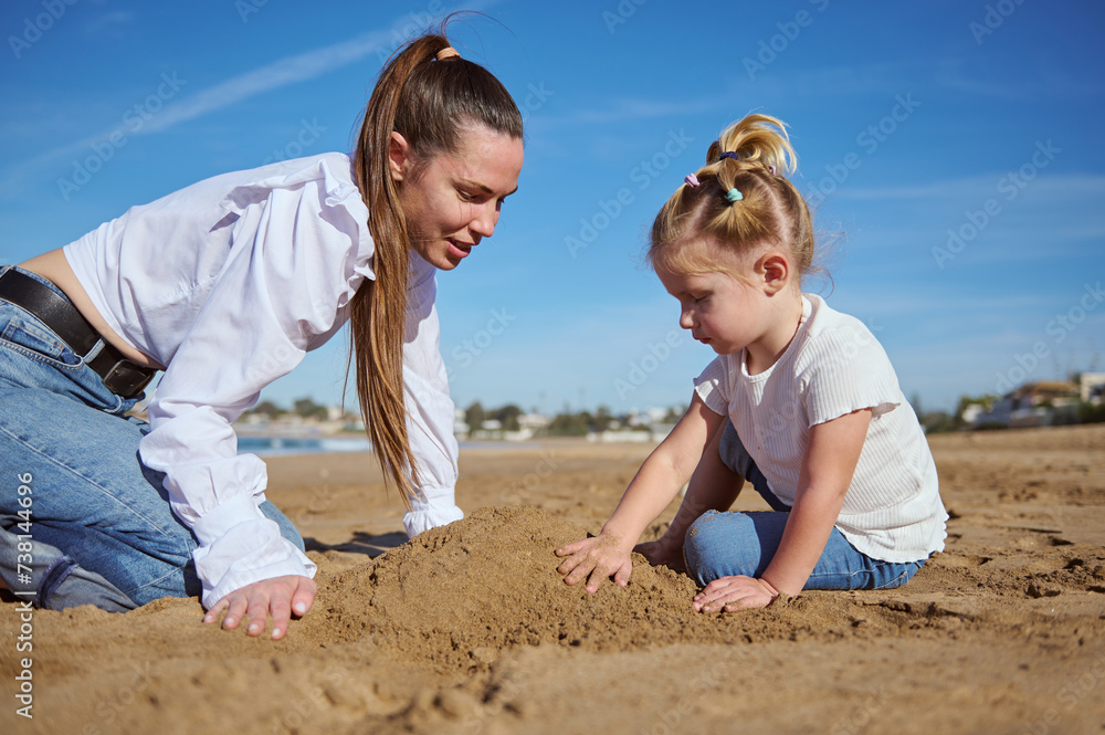 Close up portrait of happy of mother and daughter building castle in sand at beach Close up portrait of happy of mother and daughter building castle in sand at beach