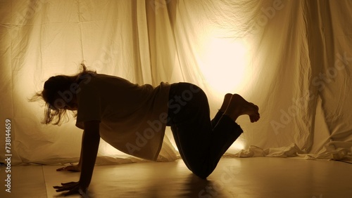 Silhouette contemporary experimental choreography concept. Female dancer performing in the studio. Young girl dancing against warm back light
