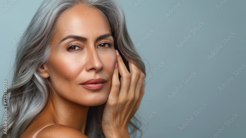 close-up portrait of an elegant senior woman with gray hair, gently touching her face and smiling subtly, set against a neutral background, suggesting a skincare or beauty theme. close-up portrait of an elegant senior woman with gray hair, gently touching her face and smiling subtly, set against a neutral background, suggesting a skincare or beauty theme.