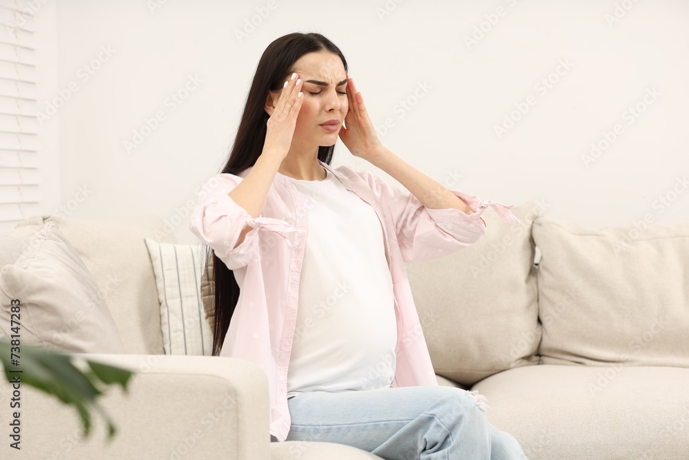 Pregnant woman suffering from headache on sofa at home Pregnant woman suffering from headache on sofa at home