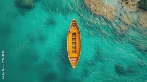 a yellow boat floating on top of a body of water next to a lush green hillside under a blue sky.