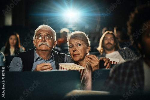 Senior couple watching a movie in the theater with popcorn photo