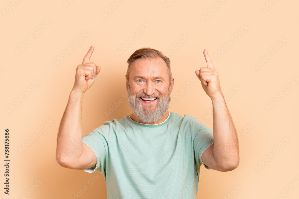 Photo of positive satisfied retired guy wear stylish clothes demonstrte offer empty space isolated on beige color background