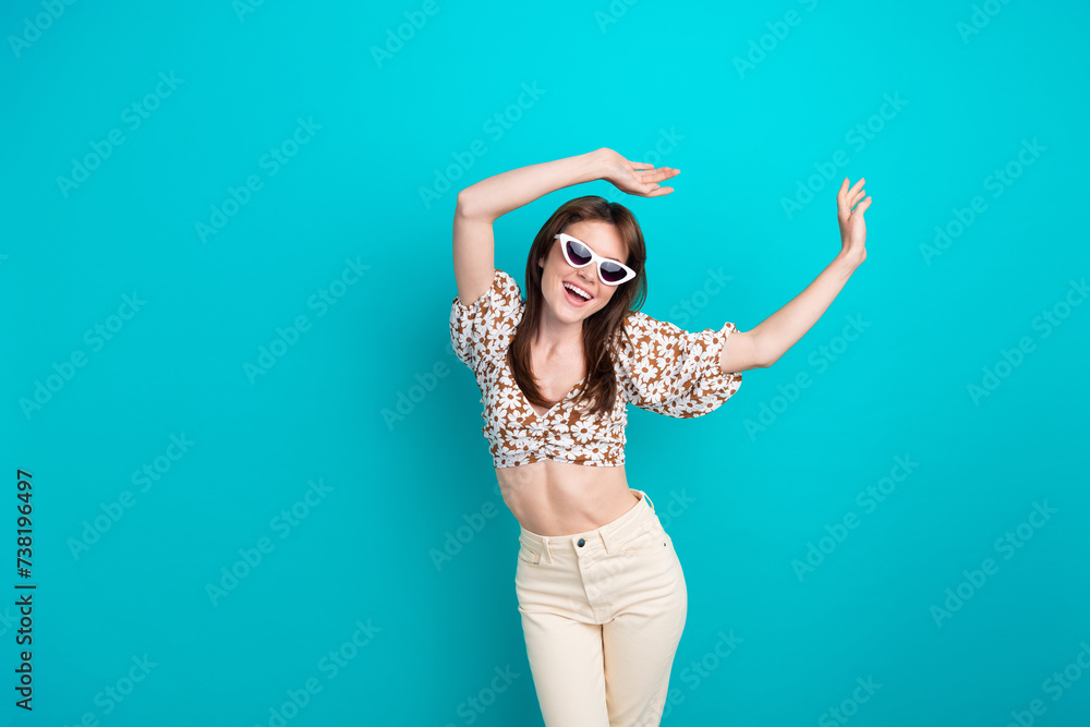 Photo of young carefree famous pop star lady in sunglasses celebrate summertime raised arms up isolated on aquamarine color background Photo of young carefree famous pop star lady in sunglasses celebrate summertime raised arms up isolated on aquamarine color background