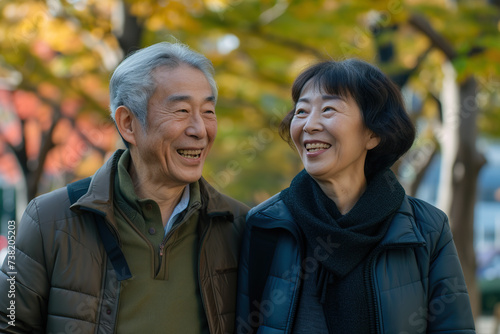 Smiling and happy senior Japanese couple enjoys a leisure walk in the city park. They radiating happiness and warmth. © AI_images
