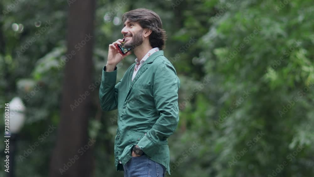 View of a young man with smartphone at daytime in a green park in the city. High quality video. View of a young man with smartphone at daytime in a green park in the city. High quality video.