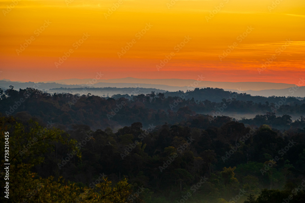 The stunning view from a tourist's standpoint as they go down a hill on a foggy trail with a hill and a background of a golden sky in Forest Park, Thailand. Rainforest. Bird's eye view. Aerial view. The stunning view from a tourist's standpoint as they go down a hill on a foggy trail with a hill and a background of a golden sky in Forest Park, Thailand. Rainforest. Bird's eye view. Aerial view.