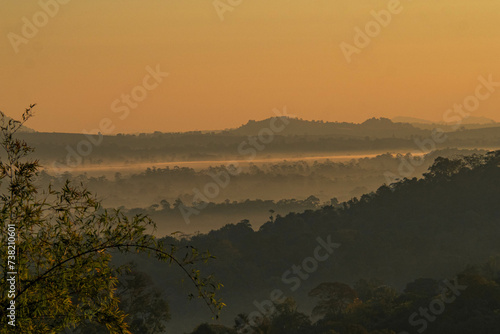 The stunning view from a tourist's standpoint as they go down a hill on a foggy trail with a hill and a background of a golden sky in Forest Park, Thailand. Rainforest. Bird's eye view. Aerial view.